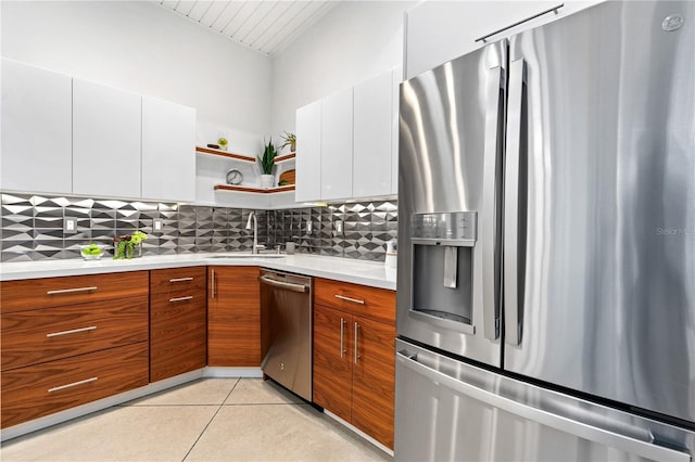 kitchen with sink, white cabinets, backsplash, light tile patterned floors, and stainless steel appliances