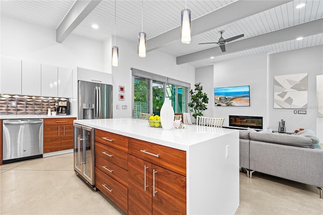 kitchen featuring appliances with stainless steel finishes, a center island, wine cooler, white cabinets, and decorative light fixtures