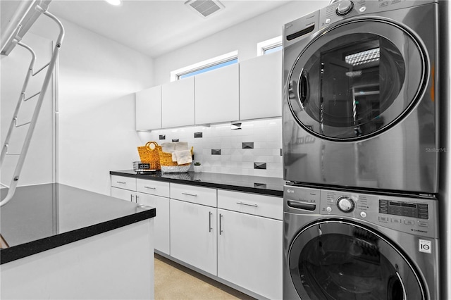 clothes washing area with cabinets and stacked washer and clothes dryer