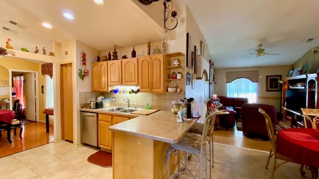 kitchen with sink, a kitchen breakfast bar, dishwasher, ceiling fan, and backsplash