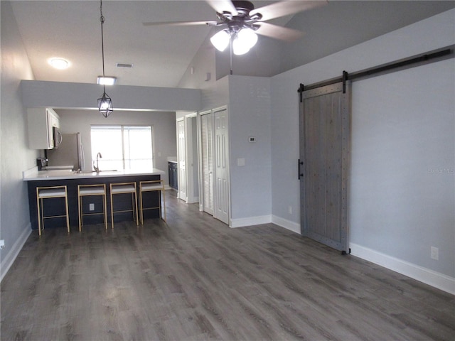 kitchen featuring dark hardwood / wood-style floors, sink, white cabinets, ceiling fan, and a barn door