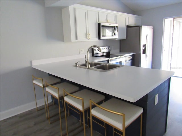 kitchen with stainless steel appliances, white cabinetry, a breakfast bar, and a healthy amount of sunlight