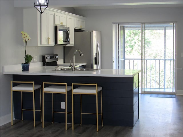 kitchen featuring a breakfast bar, sink, kitchen peninsula, stainless steel appliances, and white cabinets