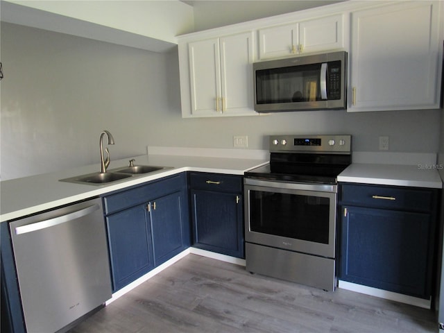 kitchen with blue cabinetry, stainless steel appliances, sink, and white cabinets