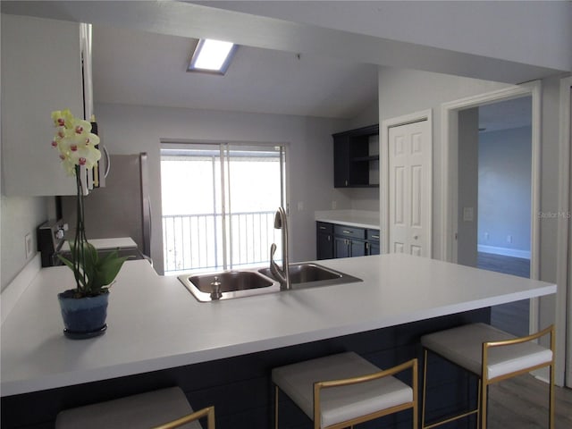 kitchen with lofted ceiling, sink, range, a kitchen breakfast bar, and kitchen peninsula