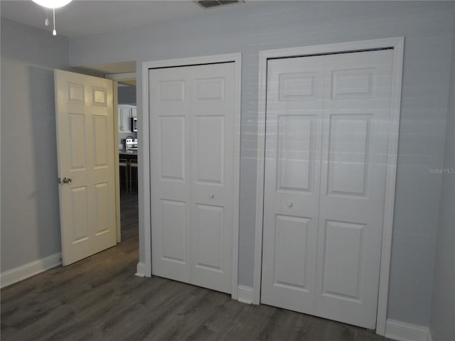 unfurnished bedroom featuring dark hardwood / wood-style flooring and multiple closets