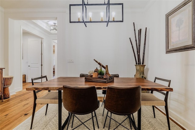 dining room with ornamental molding, a chandelier, and light hardwood / wood-style floors