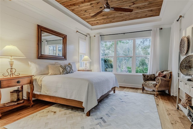 bedroom with a raised ceiling, light wood-type flooring, and wood ceiling