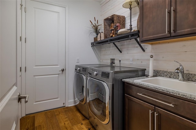 laundry room with wooden walls, sink, dark hardwood / wood-style flooring, cabinets, and independent washer and dryer