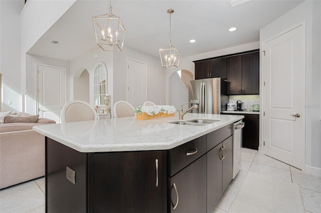 kitchen with appliances with stainless steel finishes, decorative light fixtures, sink, and a center island with sink