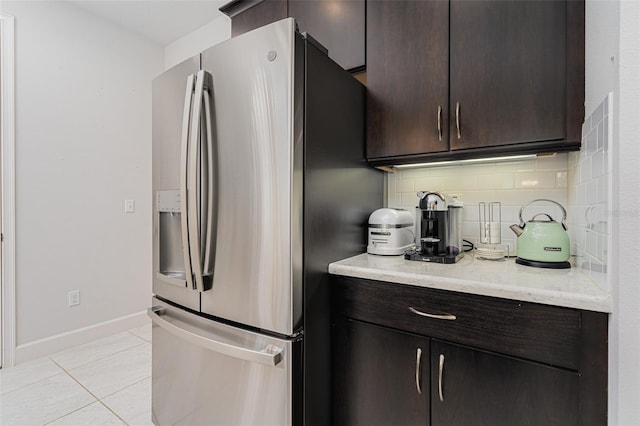 kitchen featuring tasteful backsplash, stainless steel refrigerator with ice dispenser, light tile patterned flooring, and dark brown cabinetry