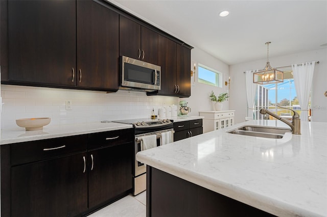 kitchen with decorative light fixtures, sink, backsplash, dark brown cabinetry, and stainless steel appliances