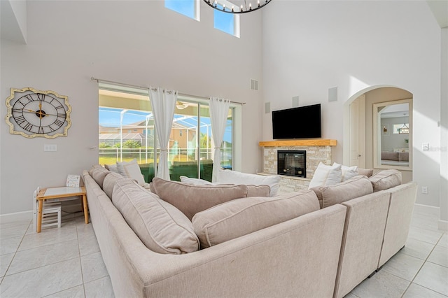 living room featuring a towering ceiling, plenty of natural light, a fireplace, and light tile patterned floors