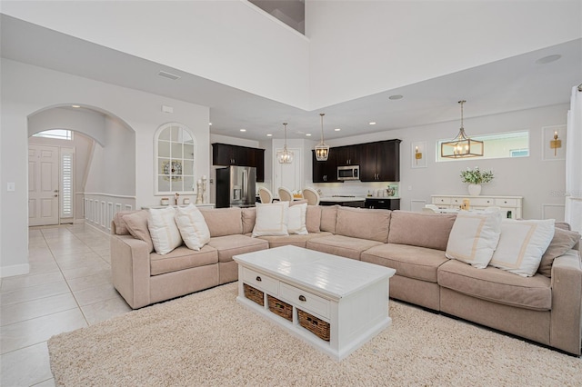 living room featuring an inviting chandelier, a high ceiling, and light tile patterned floors