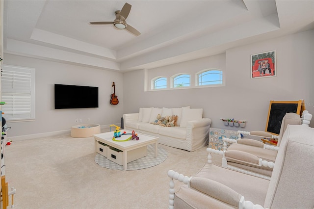 carpeted living room featuring a tray ceiling and ceiling fan