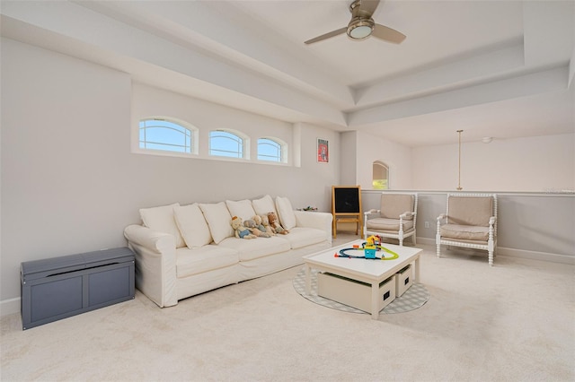 living room with a raised ceiling, carpet flooring, and ceiling fan