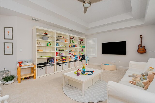 recreation room with a raised ceiling, carpet, and ceiling fan