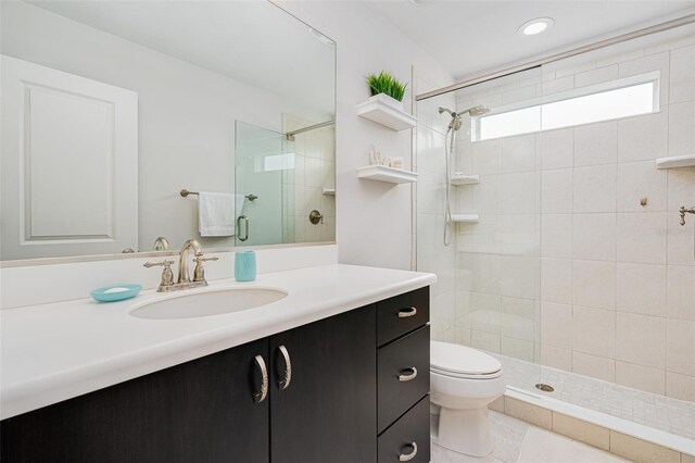 bathroom featuring vanity, tile patterned floors, toilet, and tiled shower