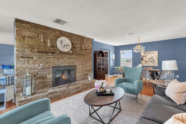 living room featuring a fireplace, a chandelier, light hardwood / wood-style floors, and a textured ceiling