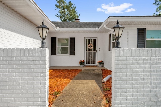 728 Vicksburg St, Deltona, FL 32725 - view of exterior entry featuring brick siding, a shingled roof, and fence