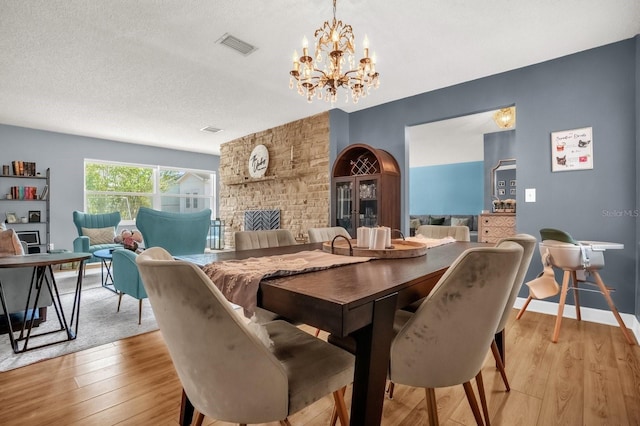 728 Vicksburg St, Deltona, FL 32725 - dining space featuring light wood finished floors, a chandelier, a fireplace, and a textured ceiling