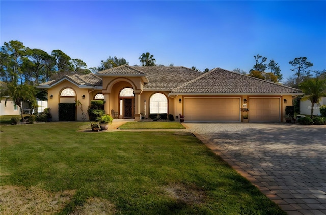 mediterranean / spanish-style house featuring a garage and a front lawn