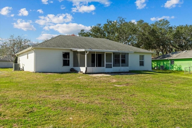 rear view of house with a sunroom, central AC, and a lawn