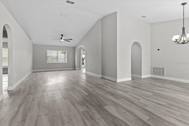 unfurnished living room with ceiling fan with notable chandelier, light hardwood / wood-style flooring, and high vaulted ceiling