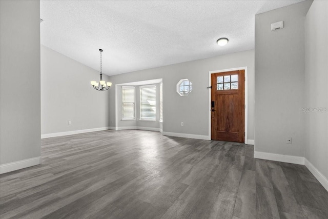 foyer with a healthy amount of sunlight, an inviting chandelier, a textured ceiling, and dark hardwood / wood-style flooring