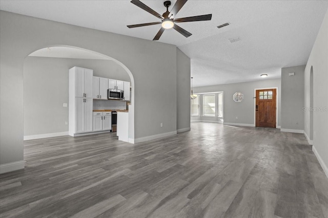 unfurnished living room featuring wood-type flooring, lofted ceiling, ceiling fan, and a textured ceiling