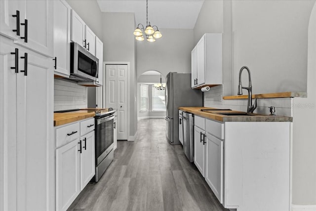 kitchen featuring stainless steel appliances, a notable chandelier, sink, and white cabinets