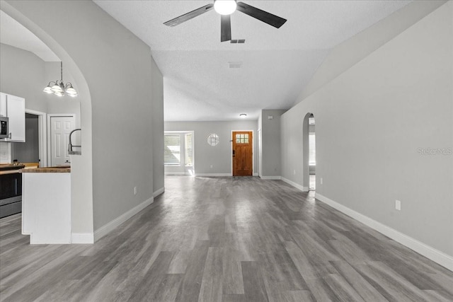 unfurnished living room with high vaulted ceiling, a textured ceiling, light hardwood / wood-style floors, and ceiling fan