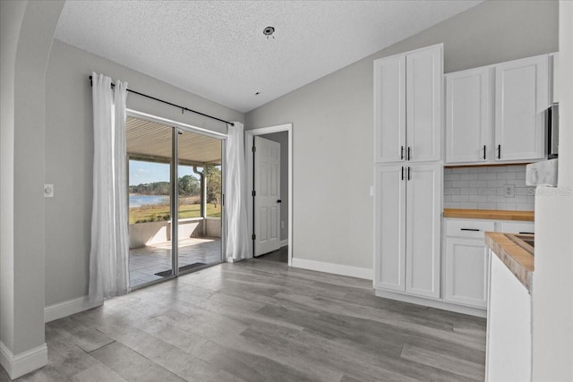 interior space featuring lofted ceiling, a textured ceiling, and light wood-type flooring