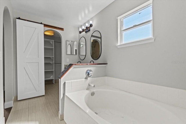 bathroom with vanity and tiled tub