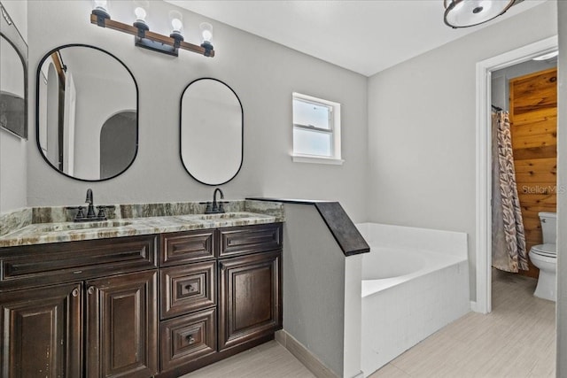 bathroom featuring vanity, a bath, and toilet