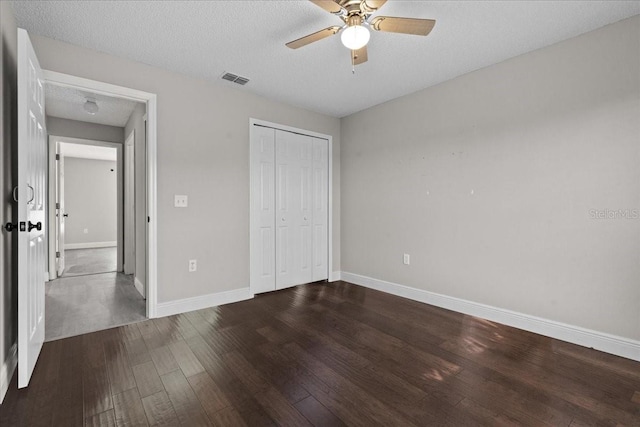 unfurnished bedroom featuring ceiling fan, a closet, dark hardwood / wood-style flooring, and a textured ceiling