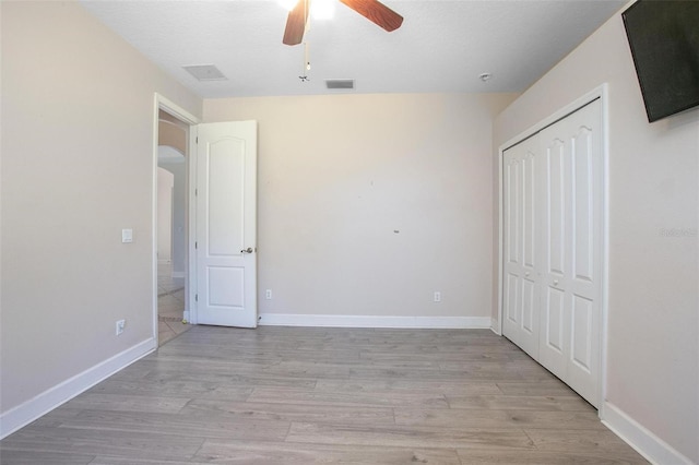 unfurnished bedroom featuring ceiling fan, a textured ceiling, light hardwood / wood-style floors, and a closet