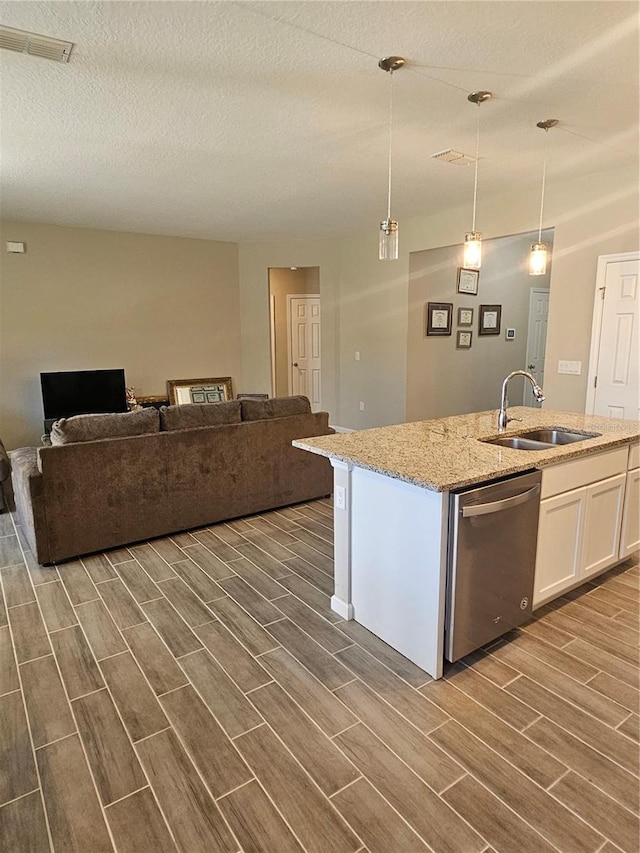 kitchen featuring dishwasher, sink, white cabinets, hanging light fixtures, and a center island with sink