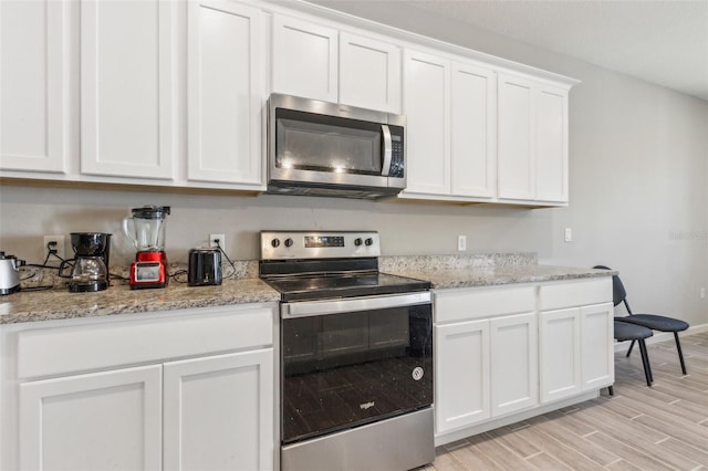 kitchen featuring light stone counters, appliances with stainless steel finishes, light wood-type flooring, and white cabinets