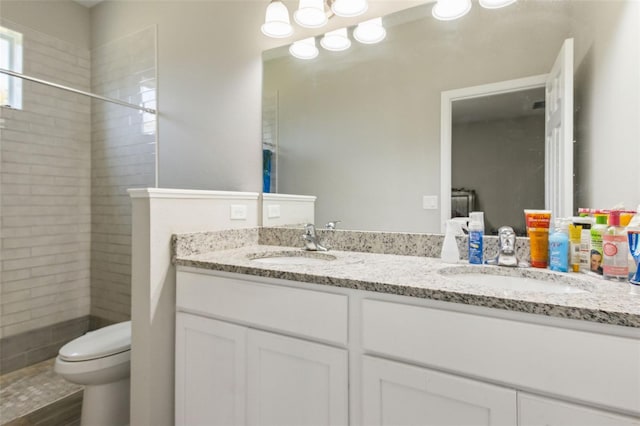 bathroom with tiled shower, vanity, and toilet