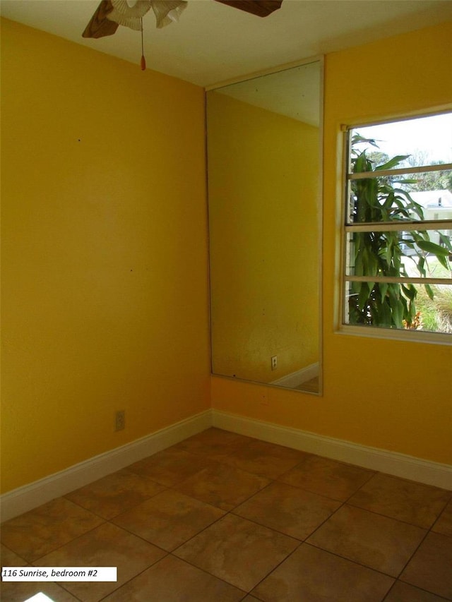 tiled empty room with plenty of natural light and ceiling fan