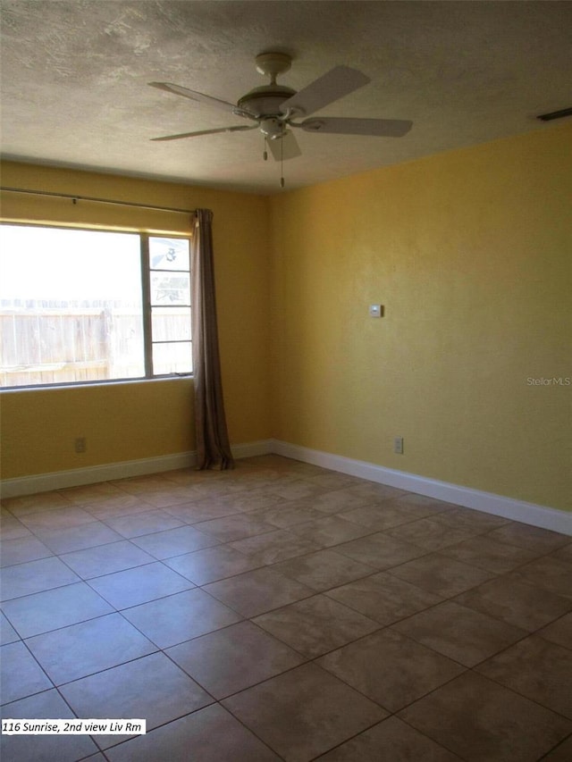 tiled empty room featuring ceiling fan