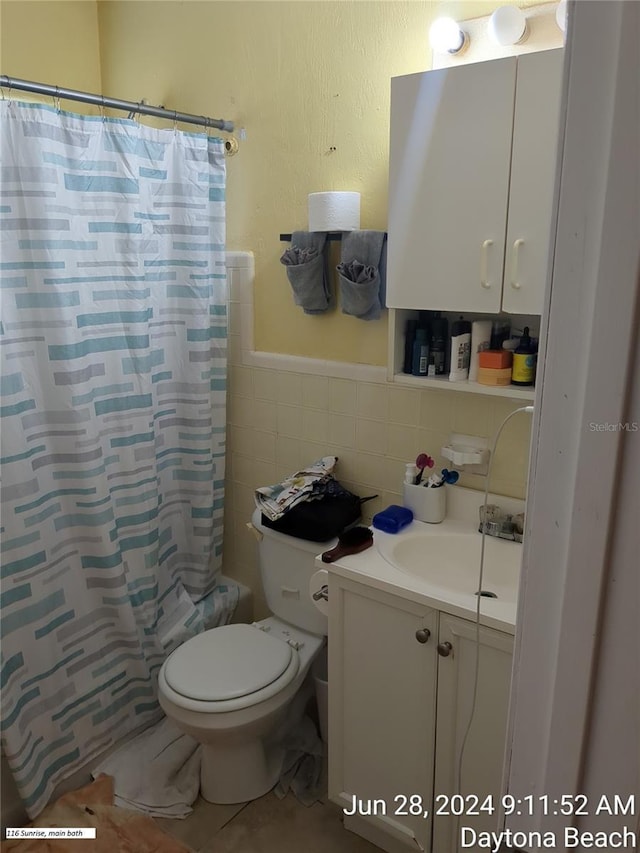 full bathroom with toilet, tile walls, vanity, shower / bath combo, and tile patterned flooring