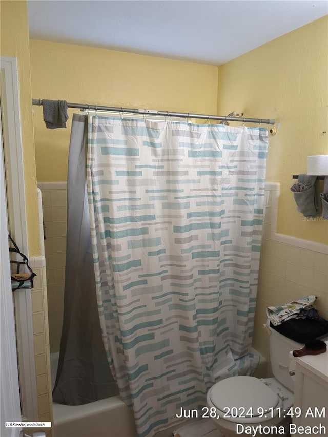 full bathroom featuring shower / tub combo with curtain, vanity, toilet, and tile walls