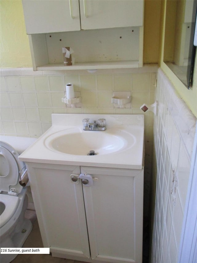 bathroom featuring vanity, toilet, and tile walls