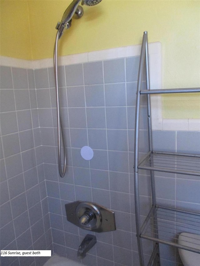 bathroom with toilet and tiled shower / bath