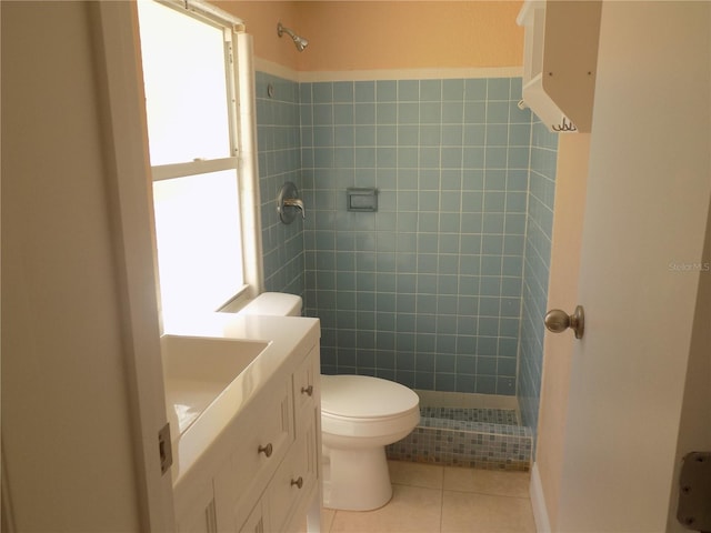 bathroom with tile patterned flooring, vanity, toilet, and tiled shower