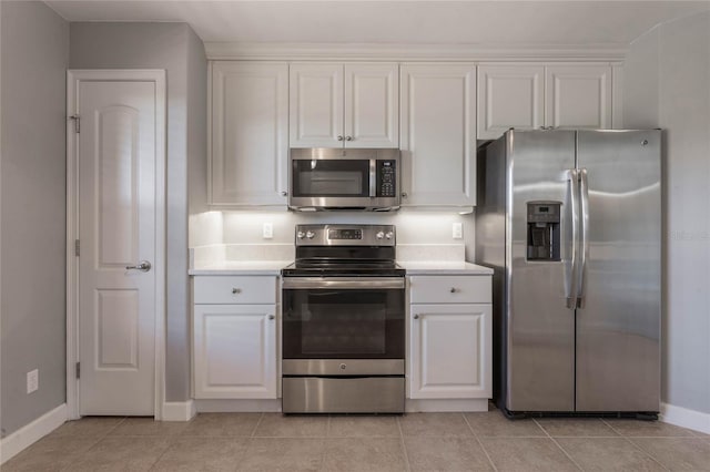 kitchen with stainless steel appliances, light tile patterned floors, and white cabinets