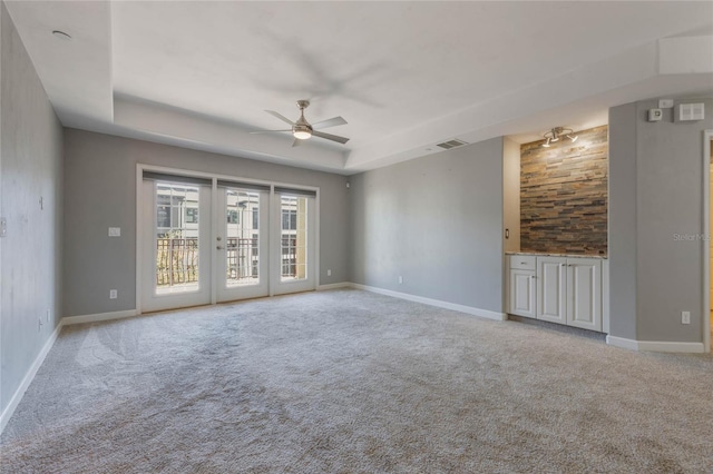 spare room with french doors, light colored carpet, a tray ceiling, and ceiling fan