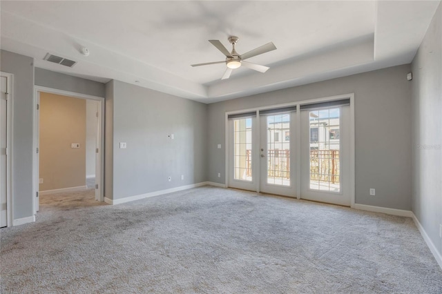 carpeted spare room with ceiling fan and a tray ceiling